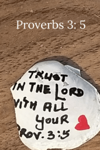 Trusting in the Lord- broken white shell on wood grain table with the words "Trust in the Lord with all your " and a red heart.