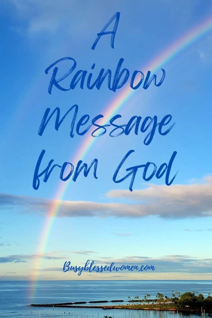 rainbow message from God- rainbow over the ocean ending in the water against a blue sky with few clouds