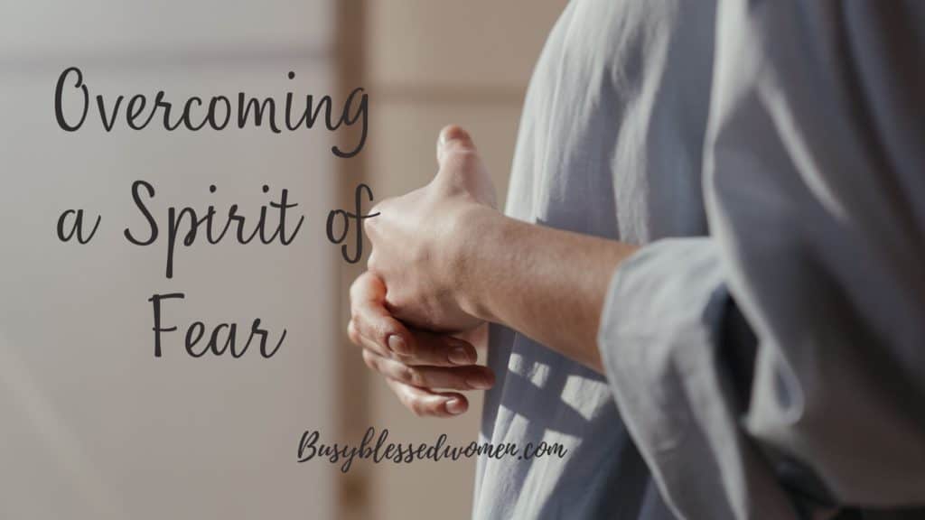 overcoming a spirit of fear- torso view of woman in oversized white blouse; hands clasped in front