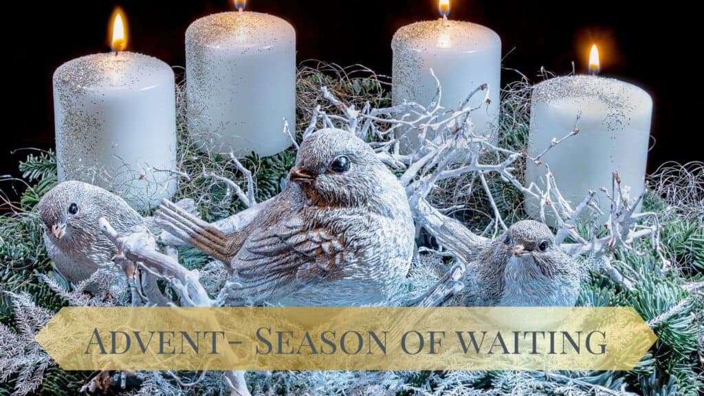 four white small lit candles in background of white twigs with 3 small artificial birds in foreground