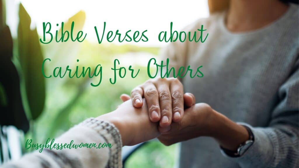 bible verses about caring for others- close up of woman in blue sweater clasping the hand of another woman; blurry greenery in background